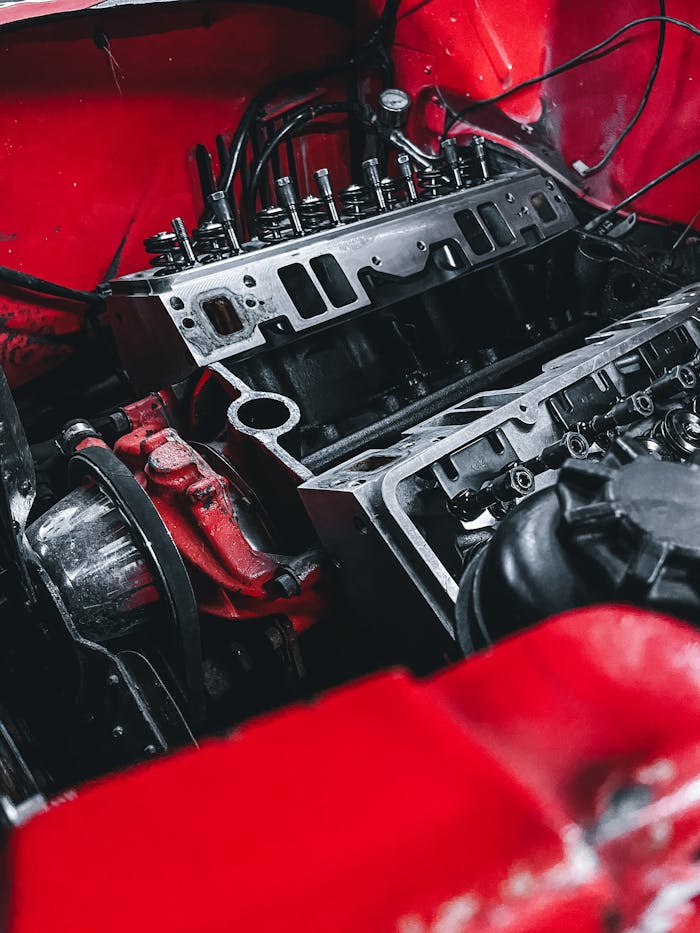 Detailed shot of a car engine within a vibrant red chassis, showcasing mechanical parts.