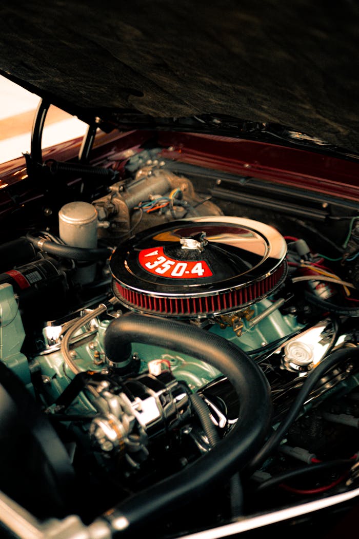 Close-up view of a classic cars engine bay with chrome details and air filter.