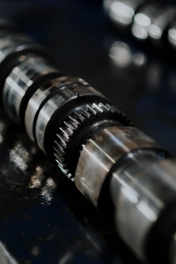 Detailed image of a camshaft showcasing gears and reflections on a dark surface.