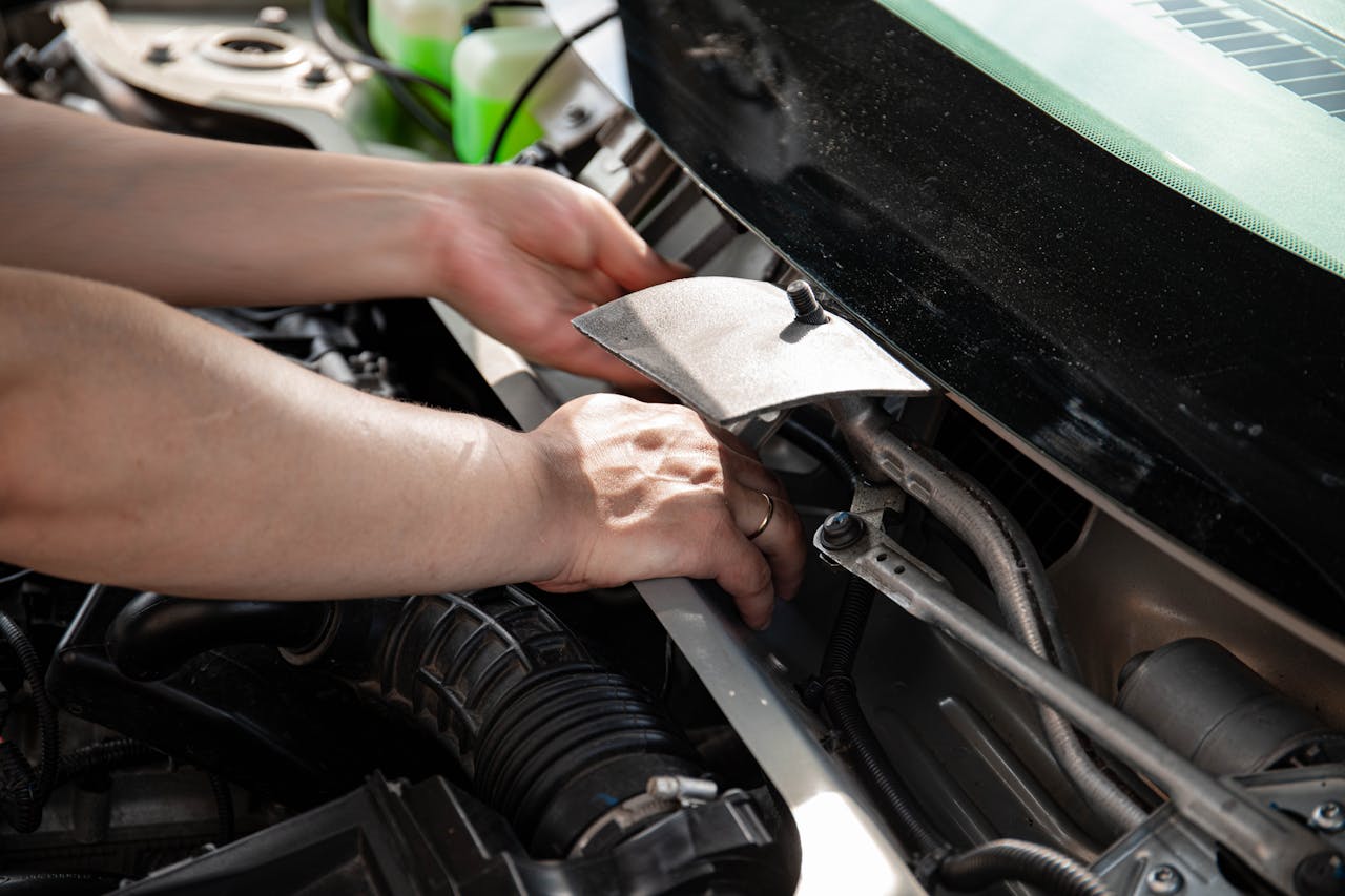 Close-up of mechanic's hands working on car engine, showcasing automotive repair skills.